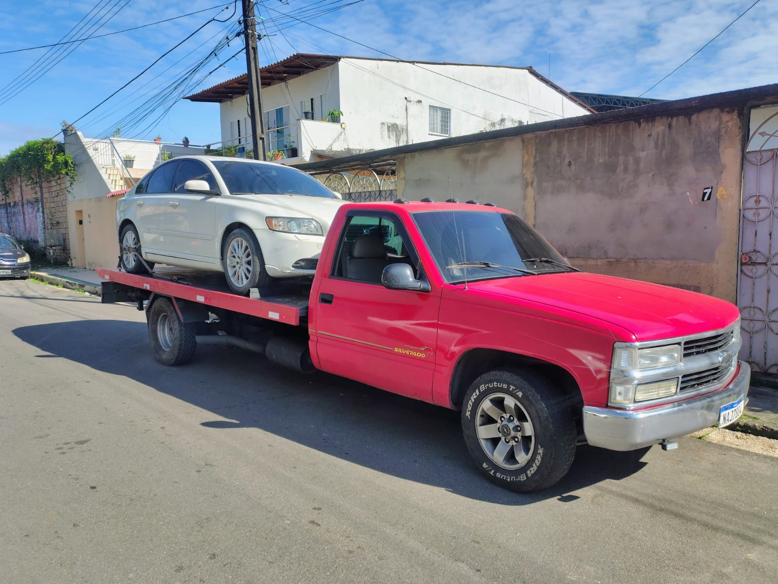 Caminhonete guincho vermelha transportando carro branco